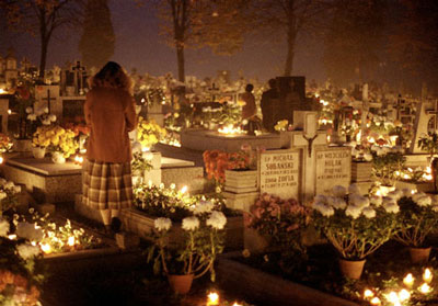 candle-lit scene in cemetery, young woman sanding, an All-Saints day scene