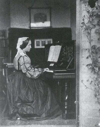 Victorian lady in long dress seated at piano