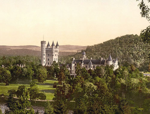 Scottish castle surrounded by trees and mountain landscape