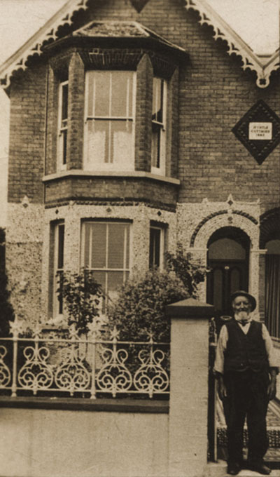 old black and white photo of gentleman standing outside a terraced house