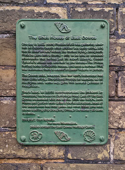 metal plaque mounted on wall containing small lines of text, green in colour