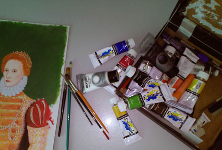 assorted art materials on desk, brushes, paints etc