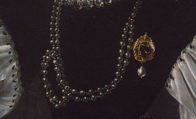 close up of painted pearl brooch and string of pearls